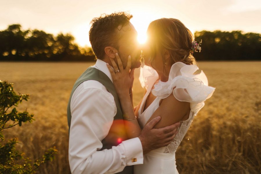 couple qui s'embrasse en peine golden hour devant un champ de blé