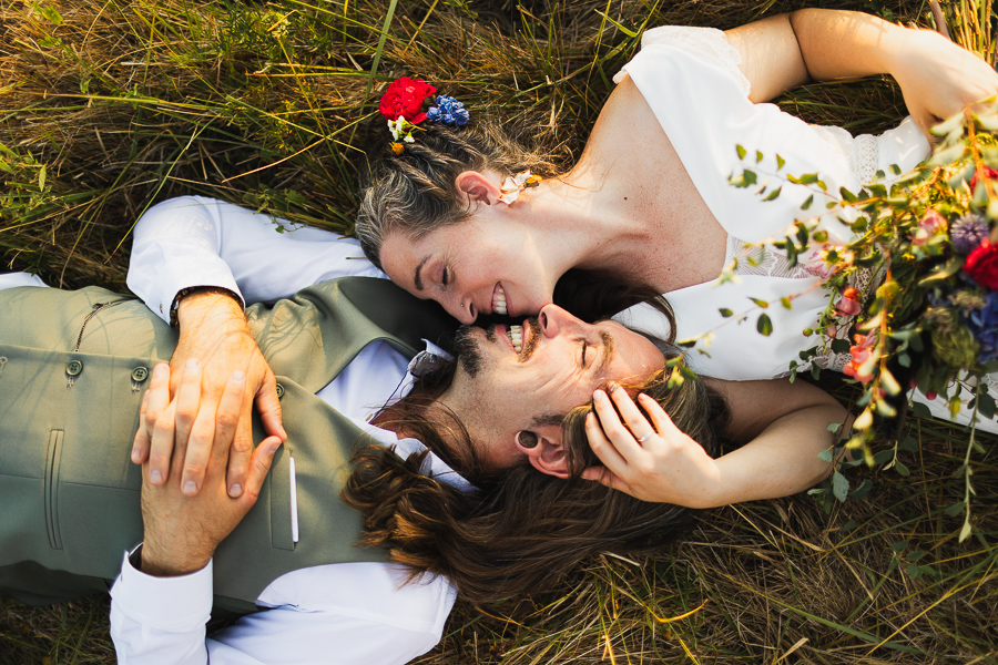 mariage bohème champêtre couple qui s'embrasse dans un champ avec bouquet de fleurs en Dordogne