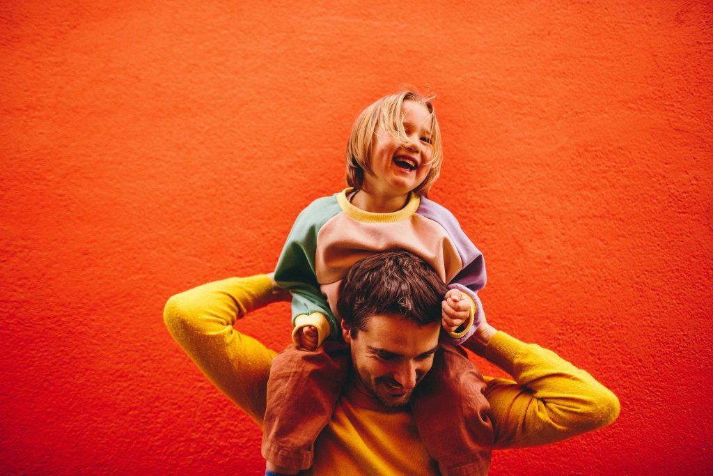papa et enfant lors d'une séance famille sur un mur coloré joie et rires 