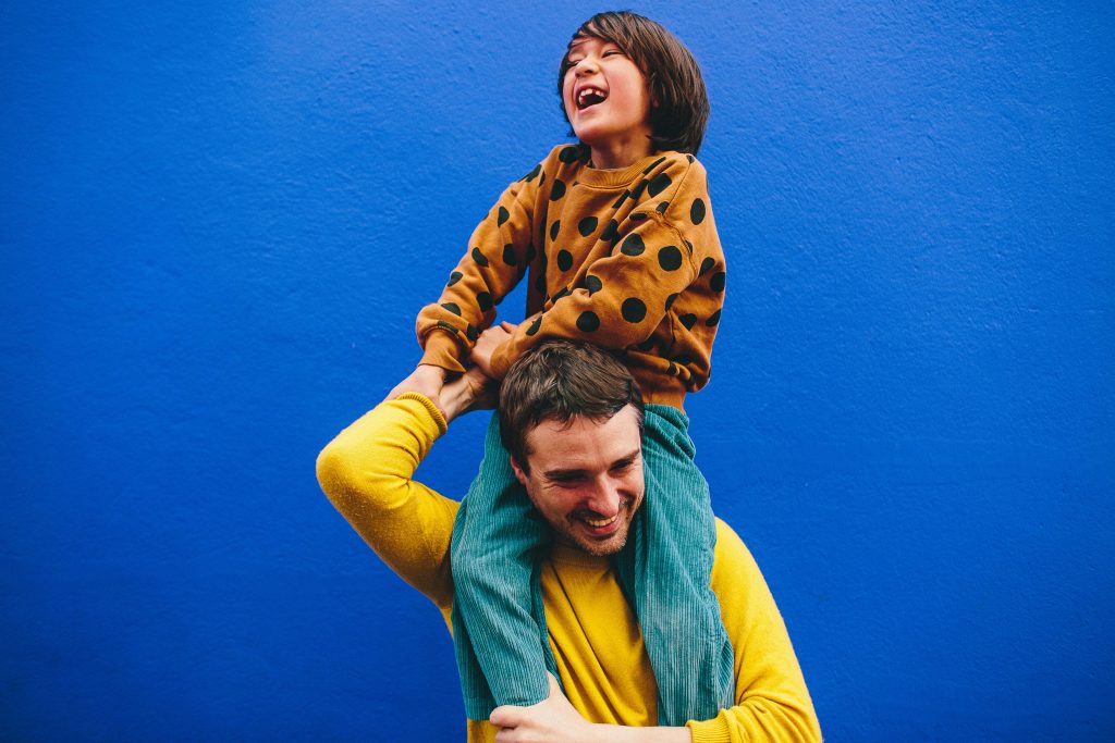 papa et enfant lors d'une séance famille sur un mur coloré joie et rires 