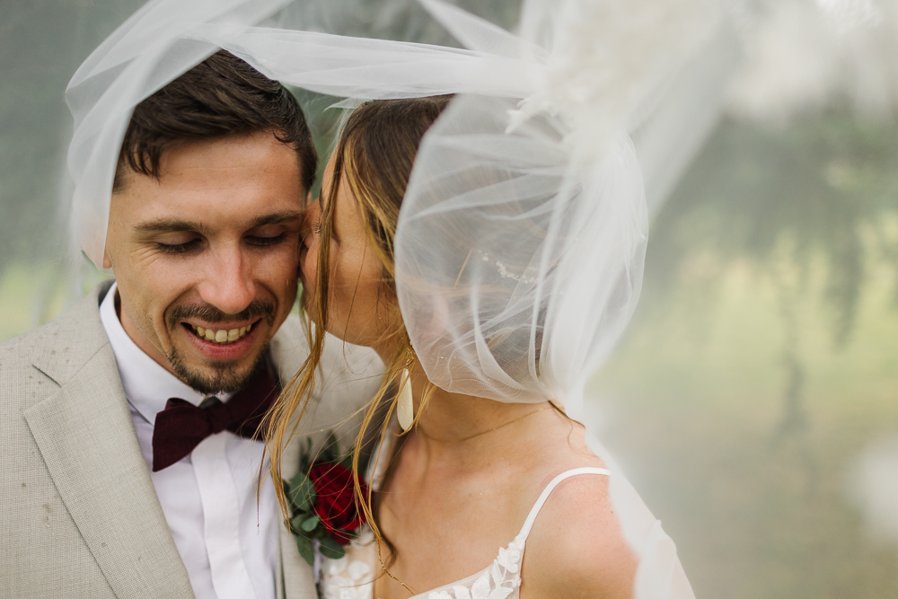 couple qui s'embrasse pendant sa séance mariage champêtre avec voile de la mariée